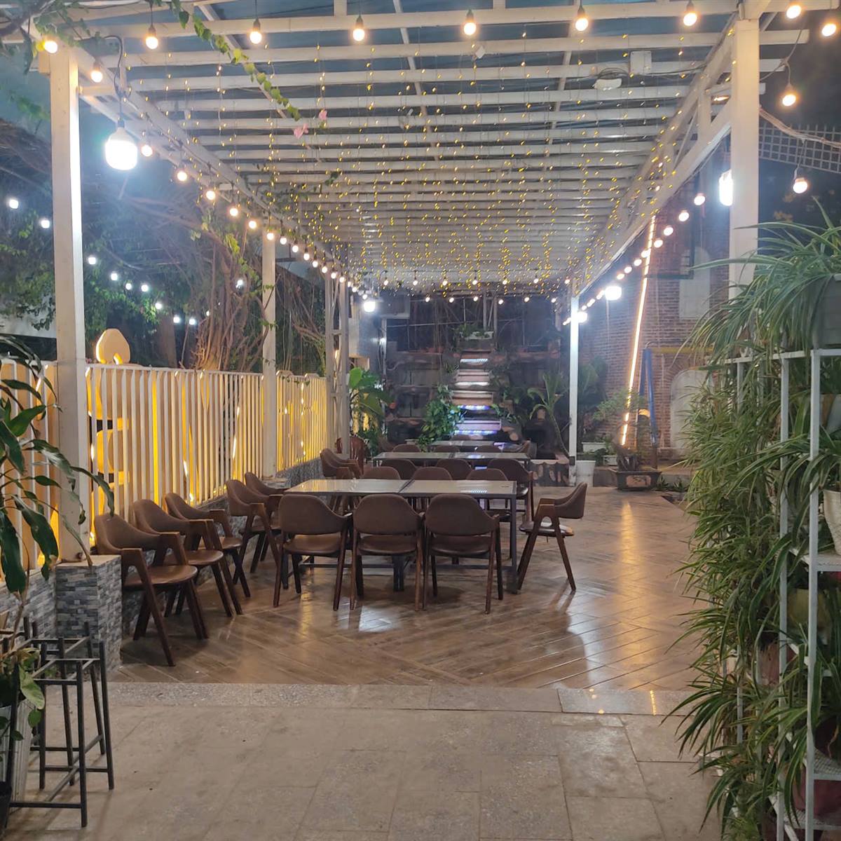 Khu ăn ngoài trời có mái pergola và đèn dây
